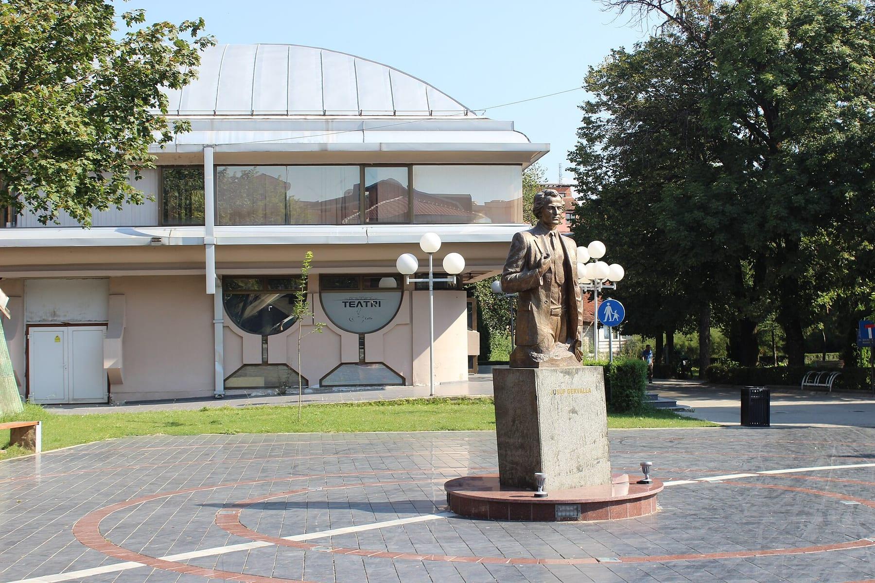 Bronze bust on a stone plinth in a square in front of the theatre building.