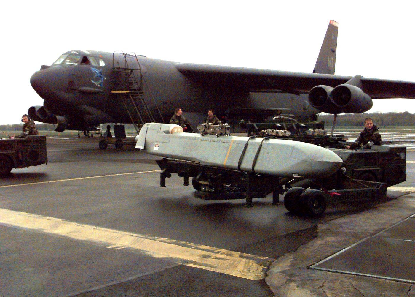 White missile on a transport trailer in front of a large bomber.