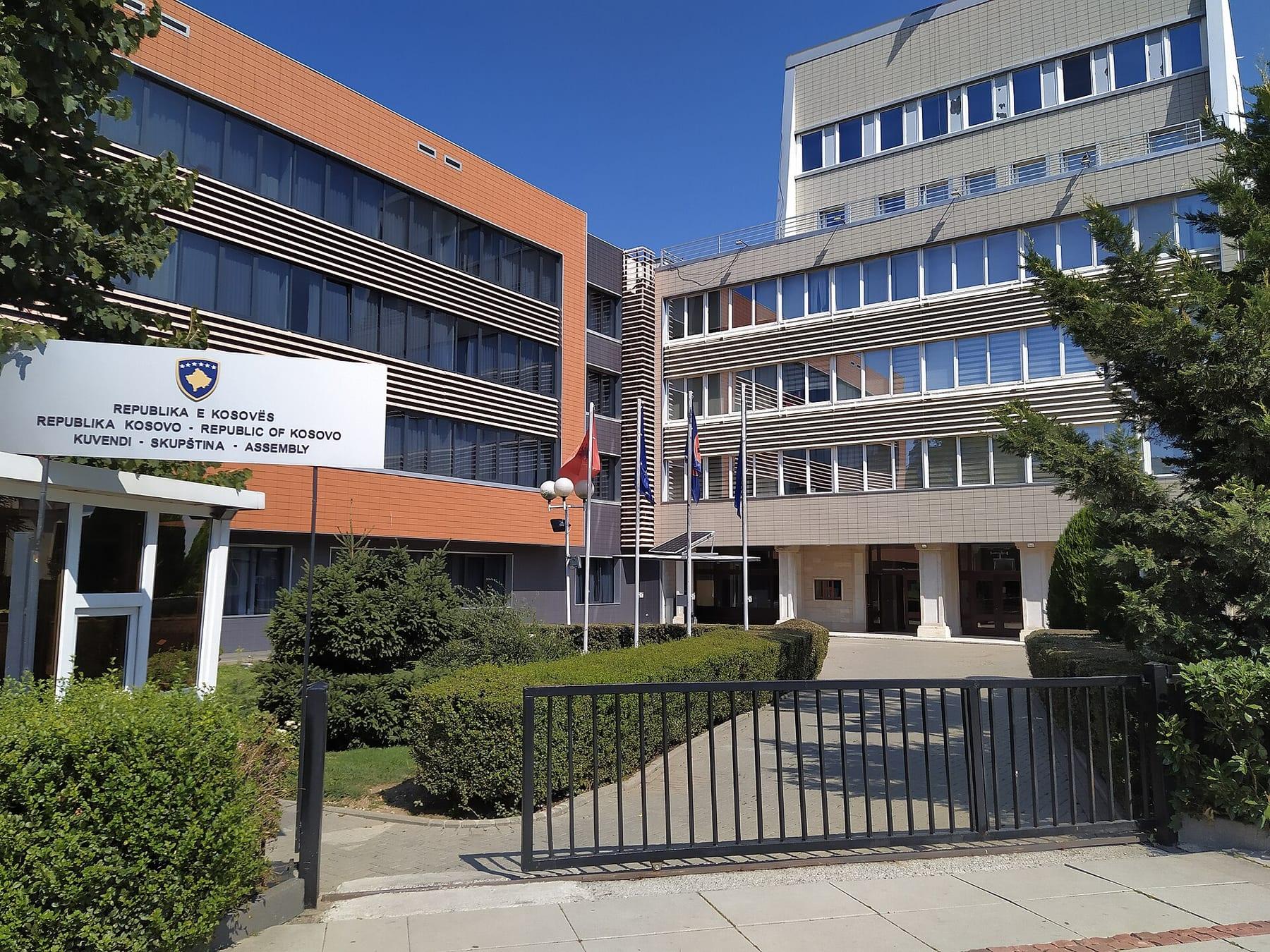 Entrance of the building with the official sign, fence and flags.