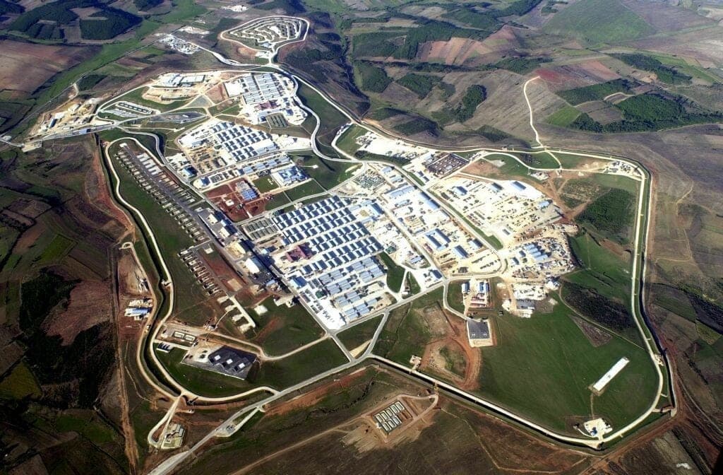 Aerial view of a large military base with a perimeter road on hills.