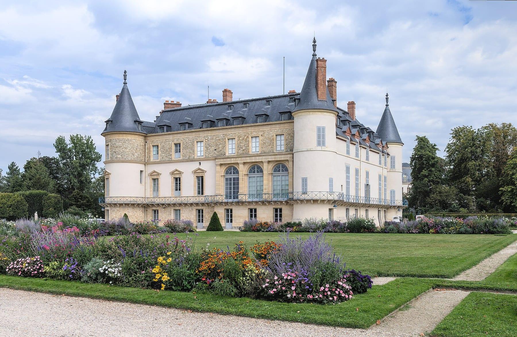 French château with turrets and a flower garden in front.
