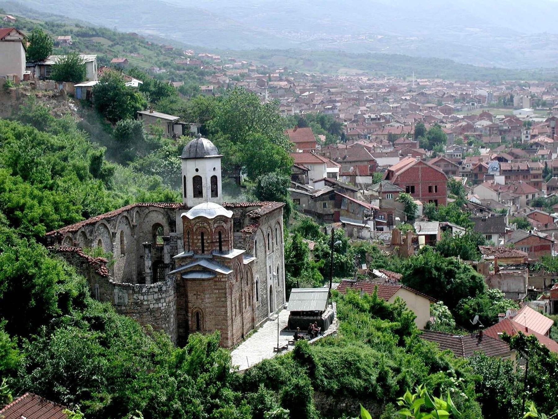 Old roofless stone church on a hillside with the town of Prizren below.