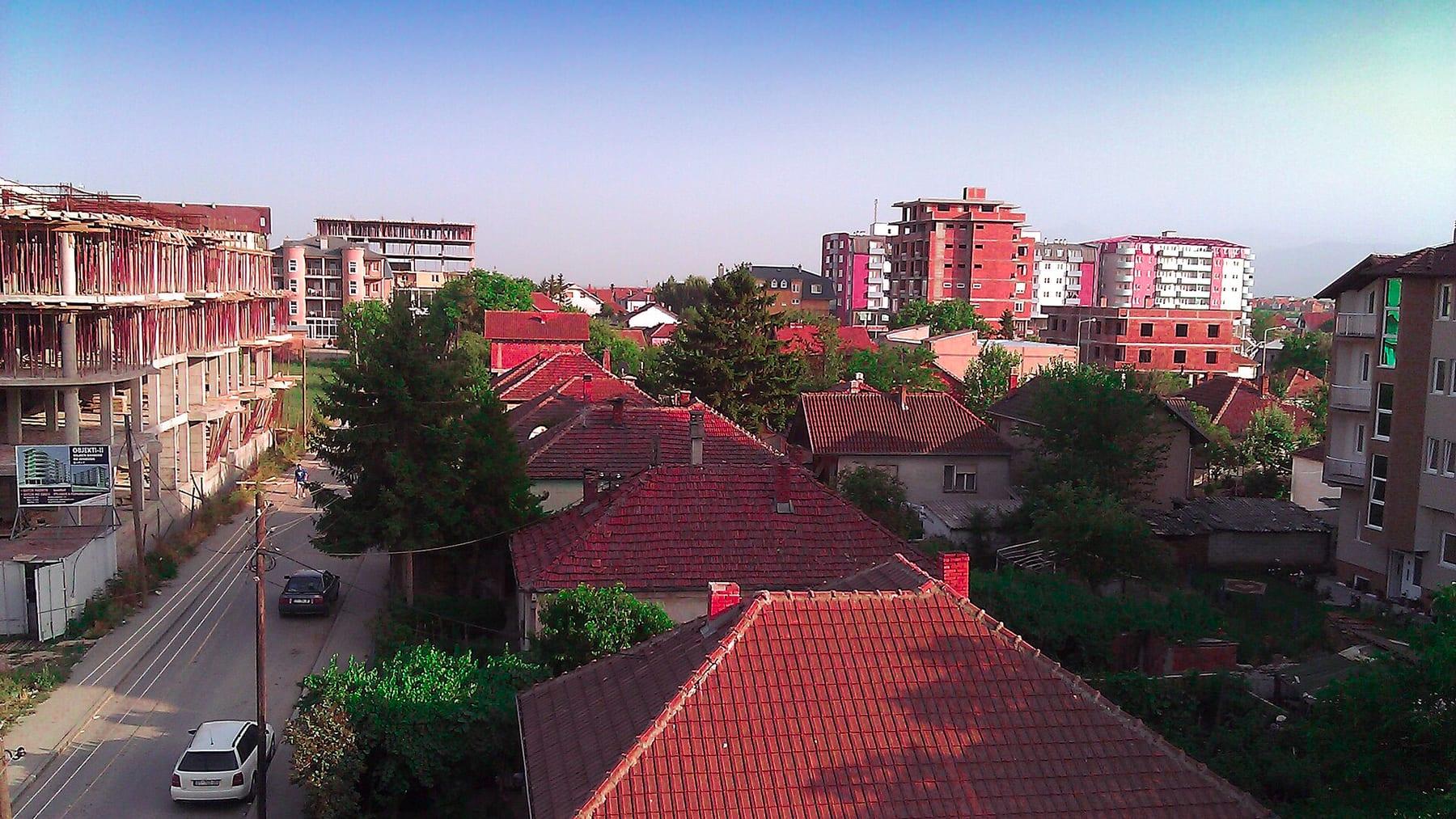 Red roofs and apartment buildings seen from above, a street on the left.
