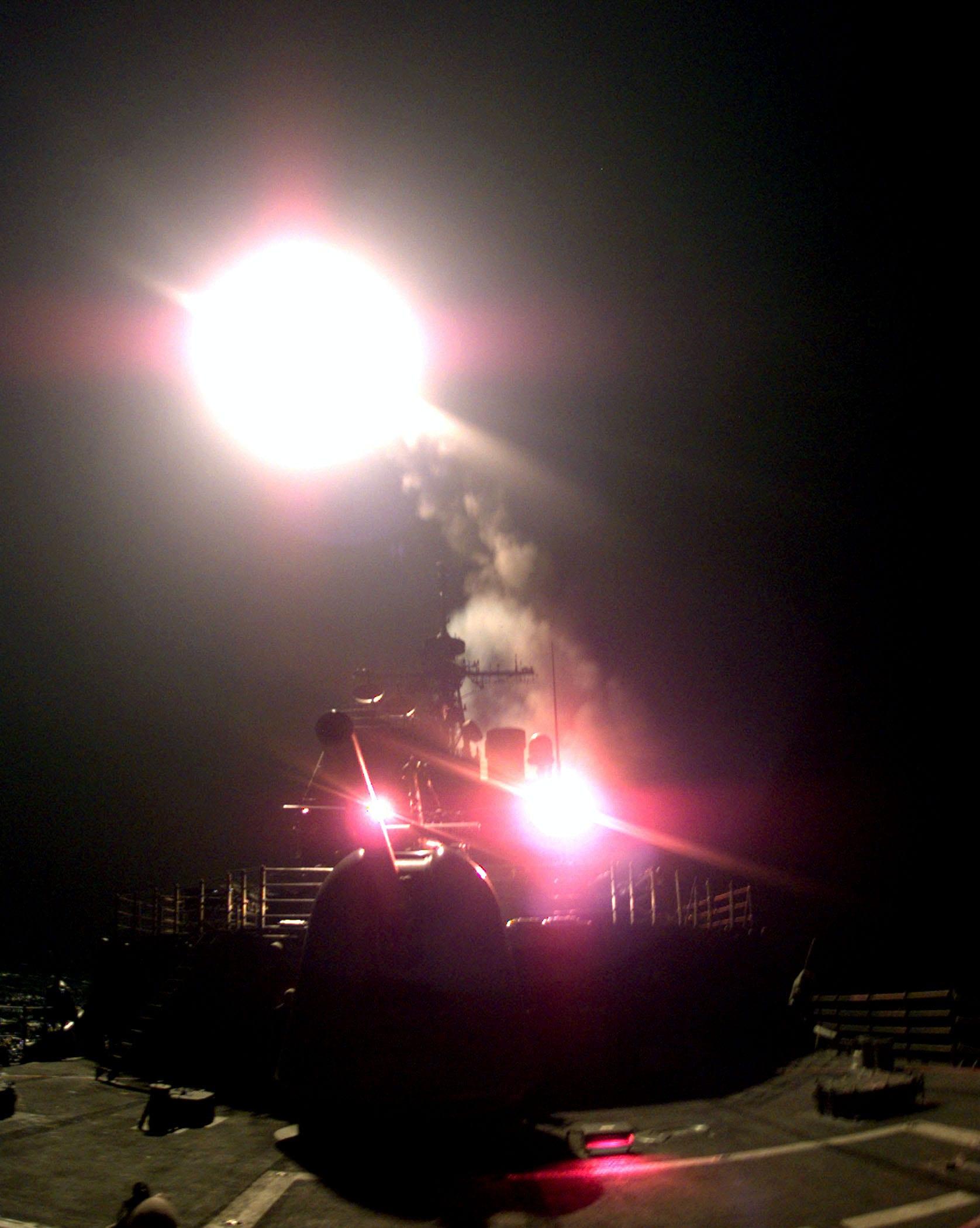 A bright flash and smoke above a ship's deck at night.