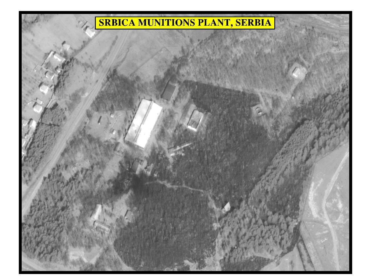 Black-and-white aerial image of an industrial compound among woods.