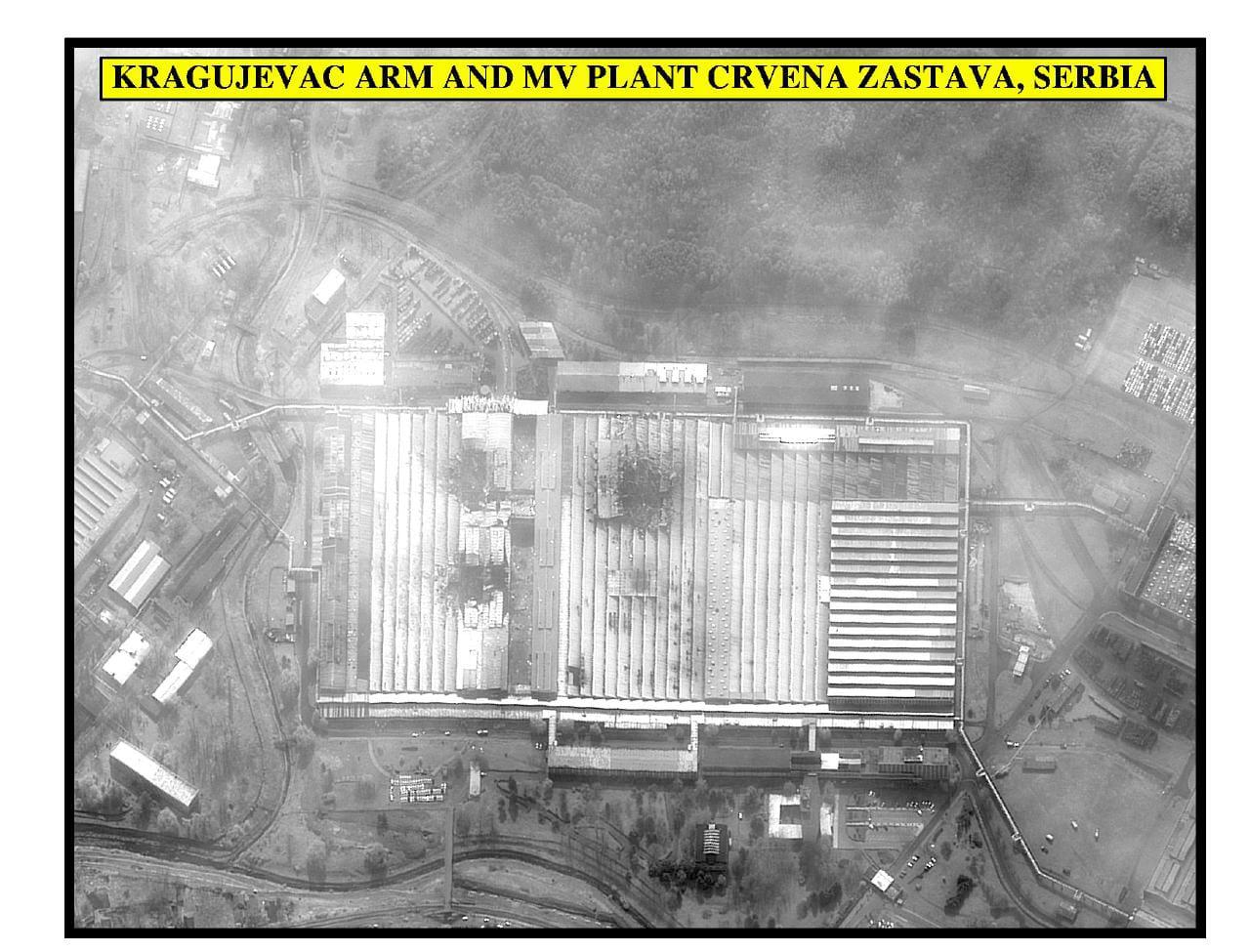 Black-and-white aerial view of a large factory complex with a damaged roof and an identifying caption.