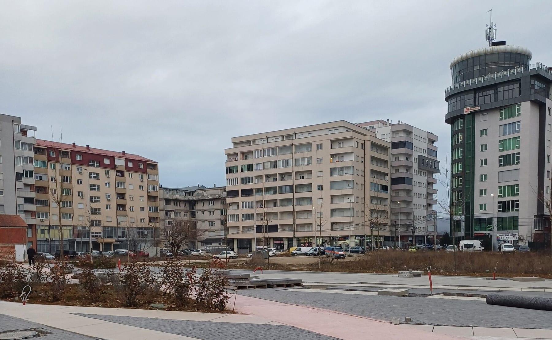 Paved square with apartment blocks and a tall tower-like building on the right.