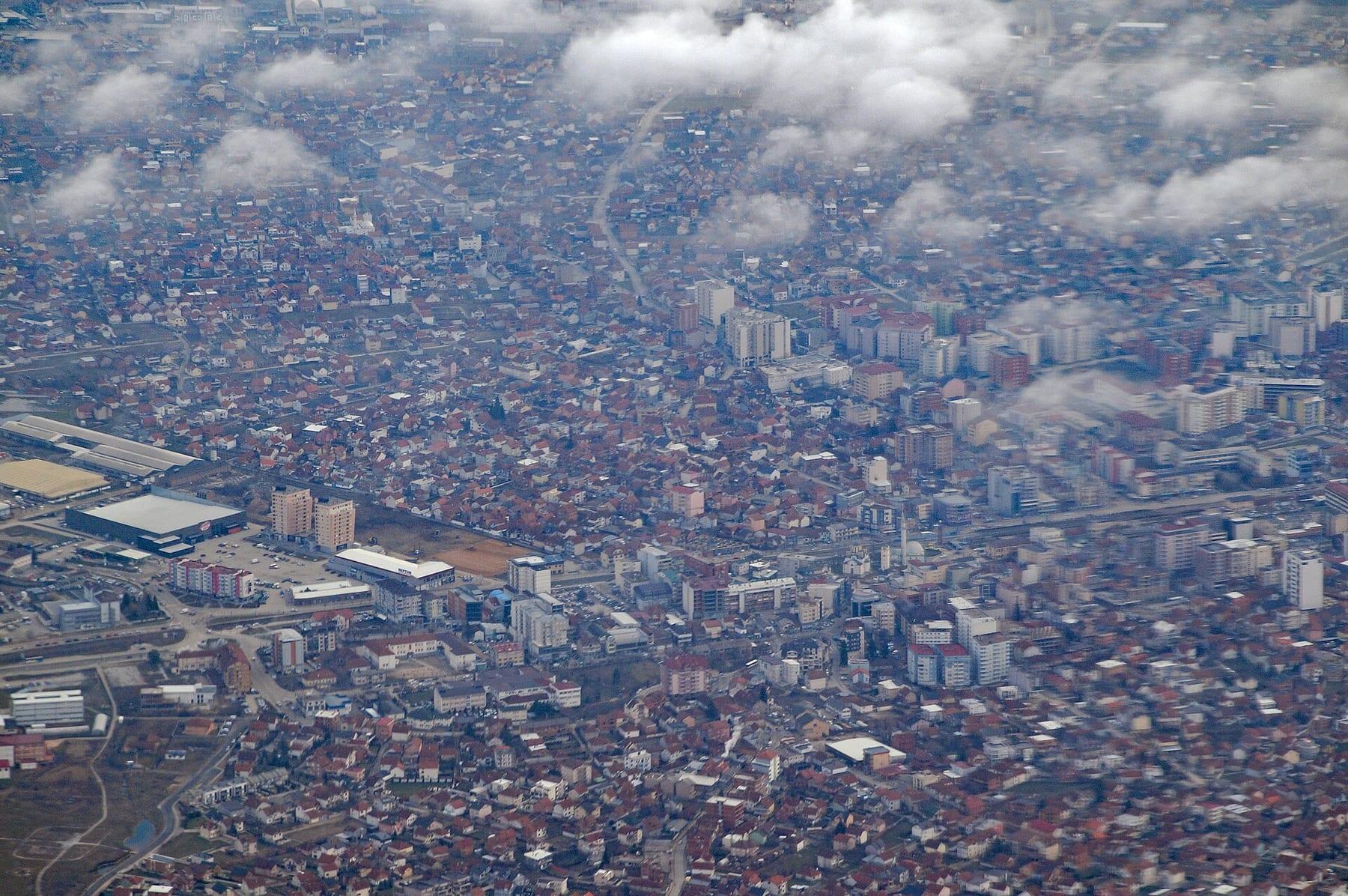 Aerial view of the dense red-roofed city with scattered clouds.
