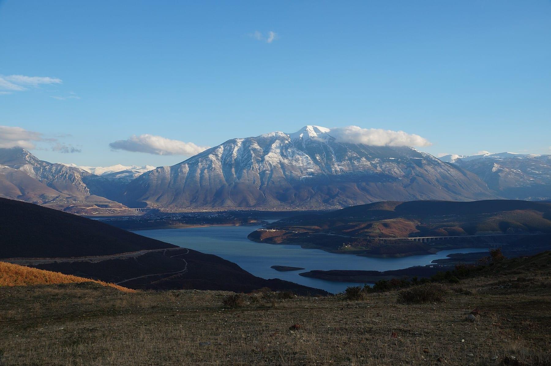 Lake and town beneath a large snow-covered mountain.