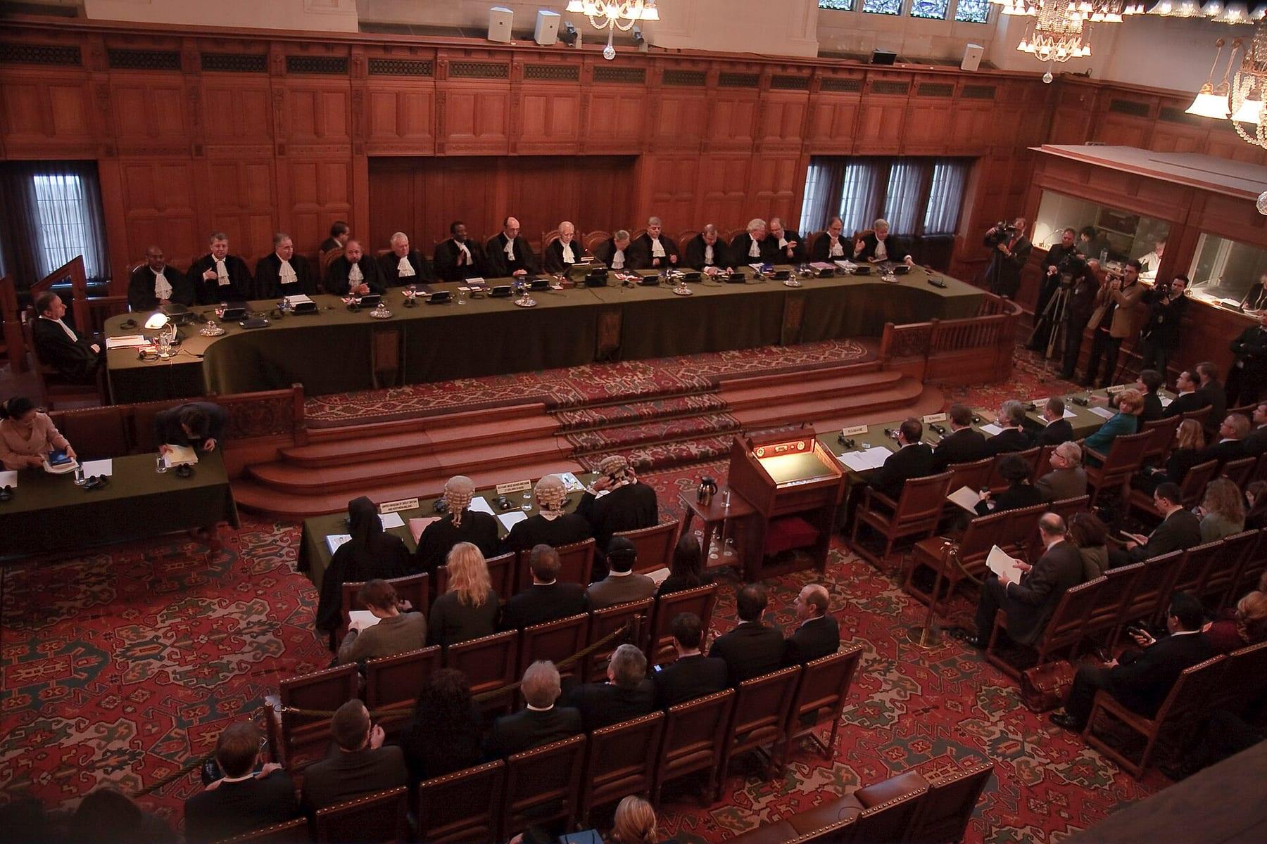Courtroom with judges seated at a long bench and delegations facing them.