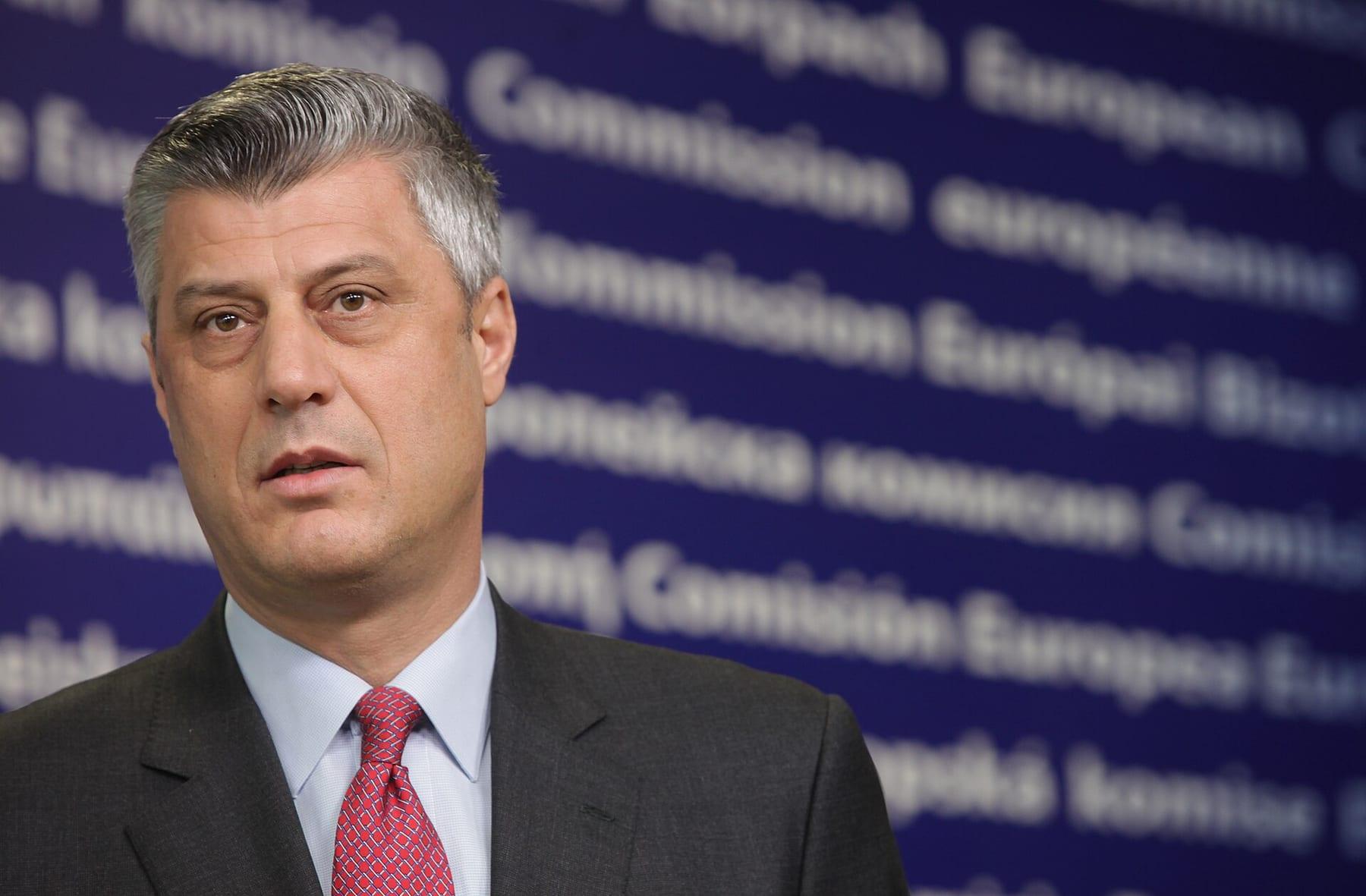 Portrait of a man in a suit and red tie in front of a blue European Commission backdrop.