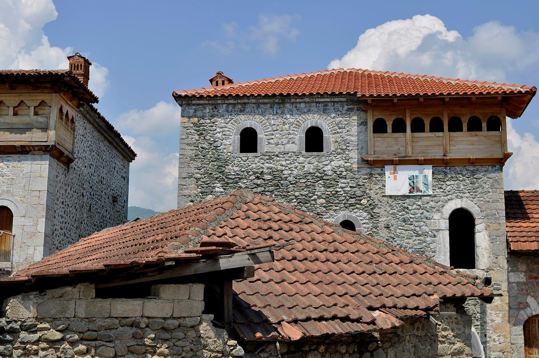 Traditional stone tower houses with tiled roofs and a wooden balcony.