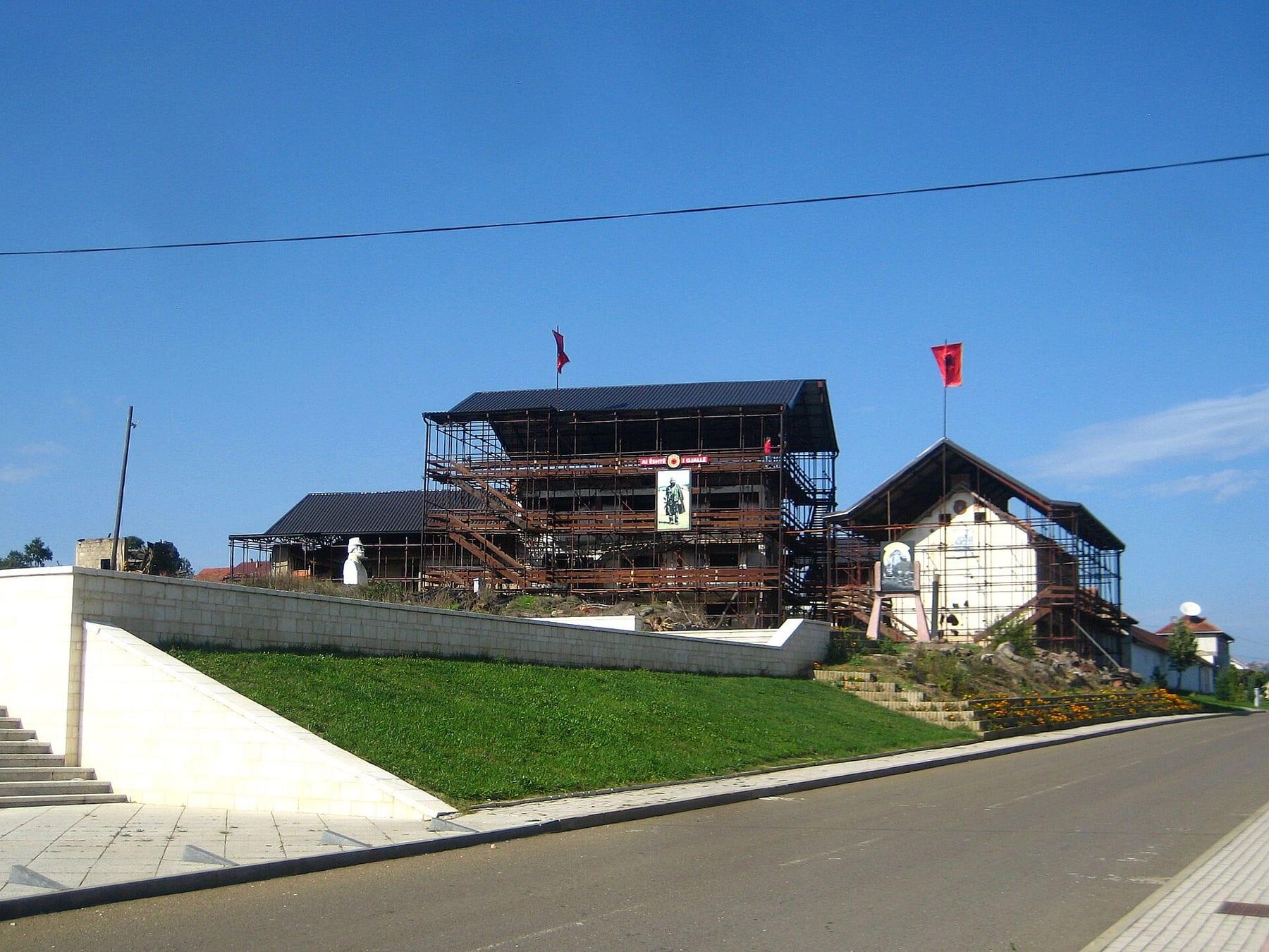 The scaffold-covered houses on a rise, seen from the road.
