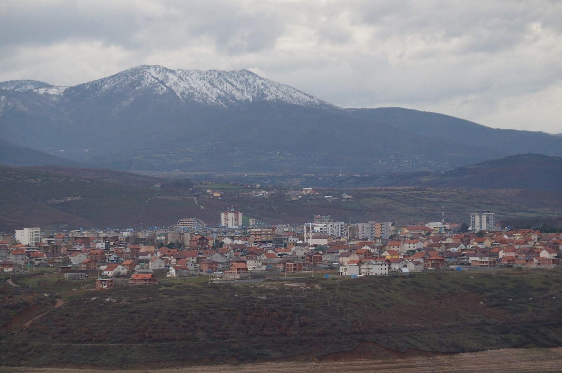 The town with apartment blocks below a snow-capped mountain.
