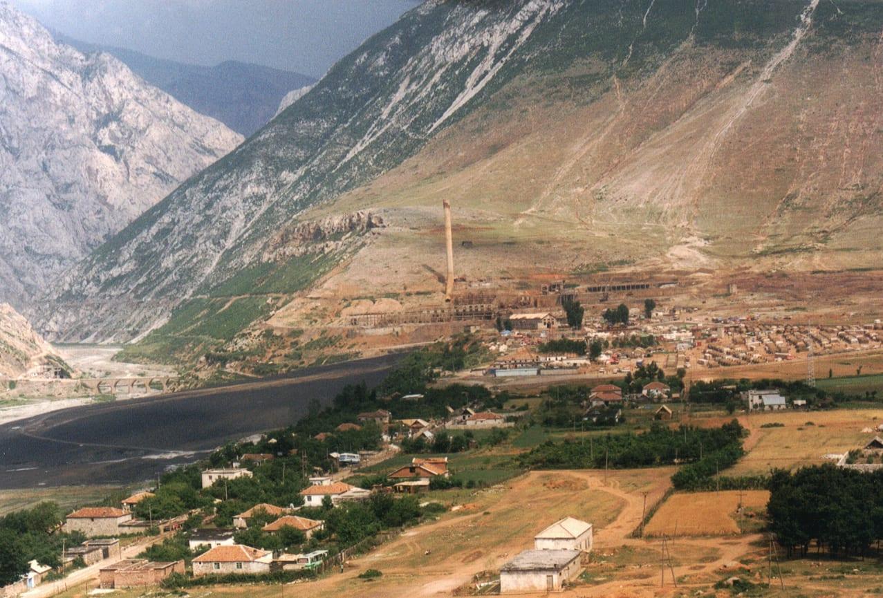 View from above of a mountain valley with a tent camp beside a river.