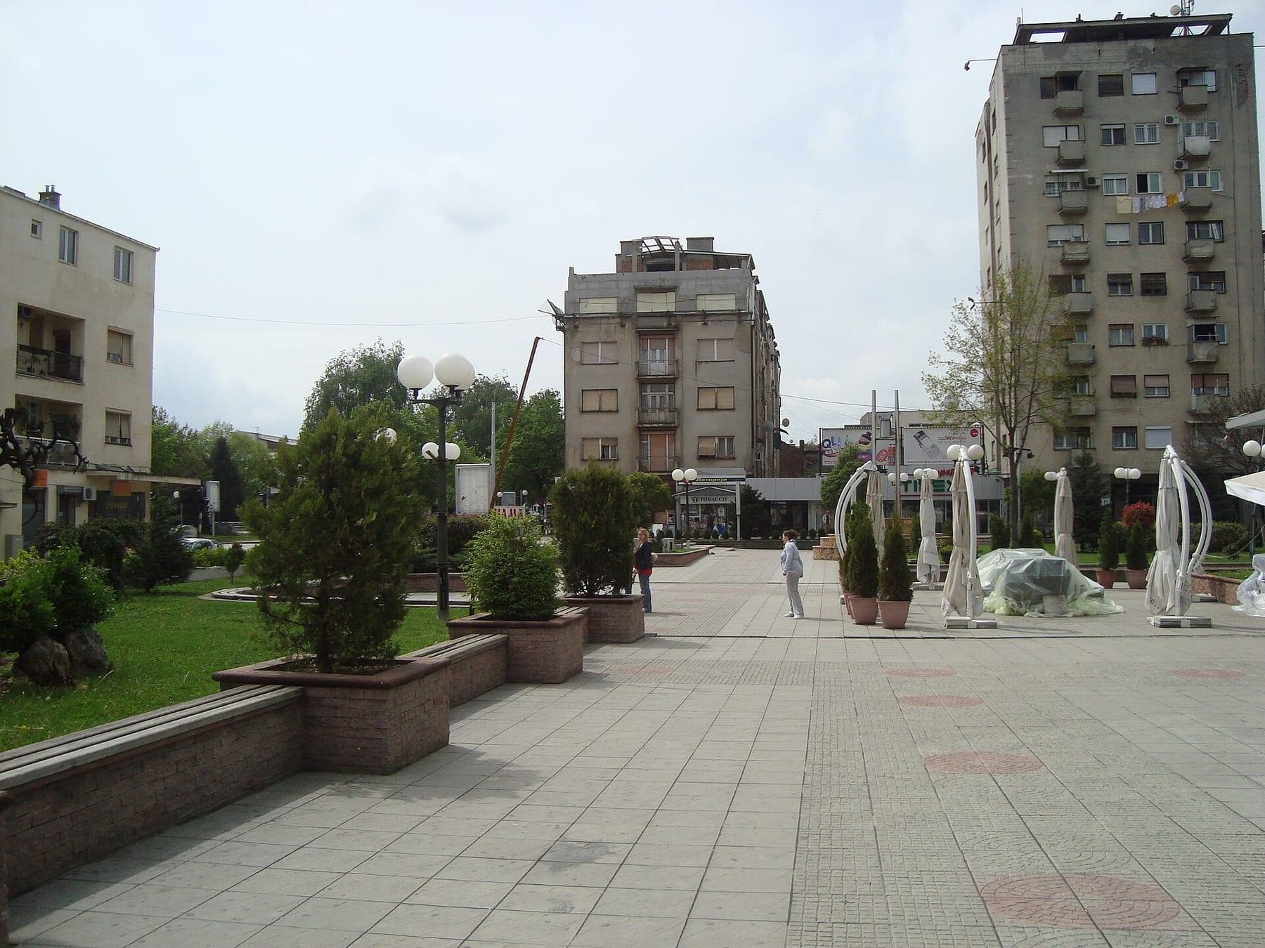 Pedestrian square with greenery and apartment blocks.
