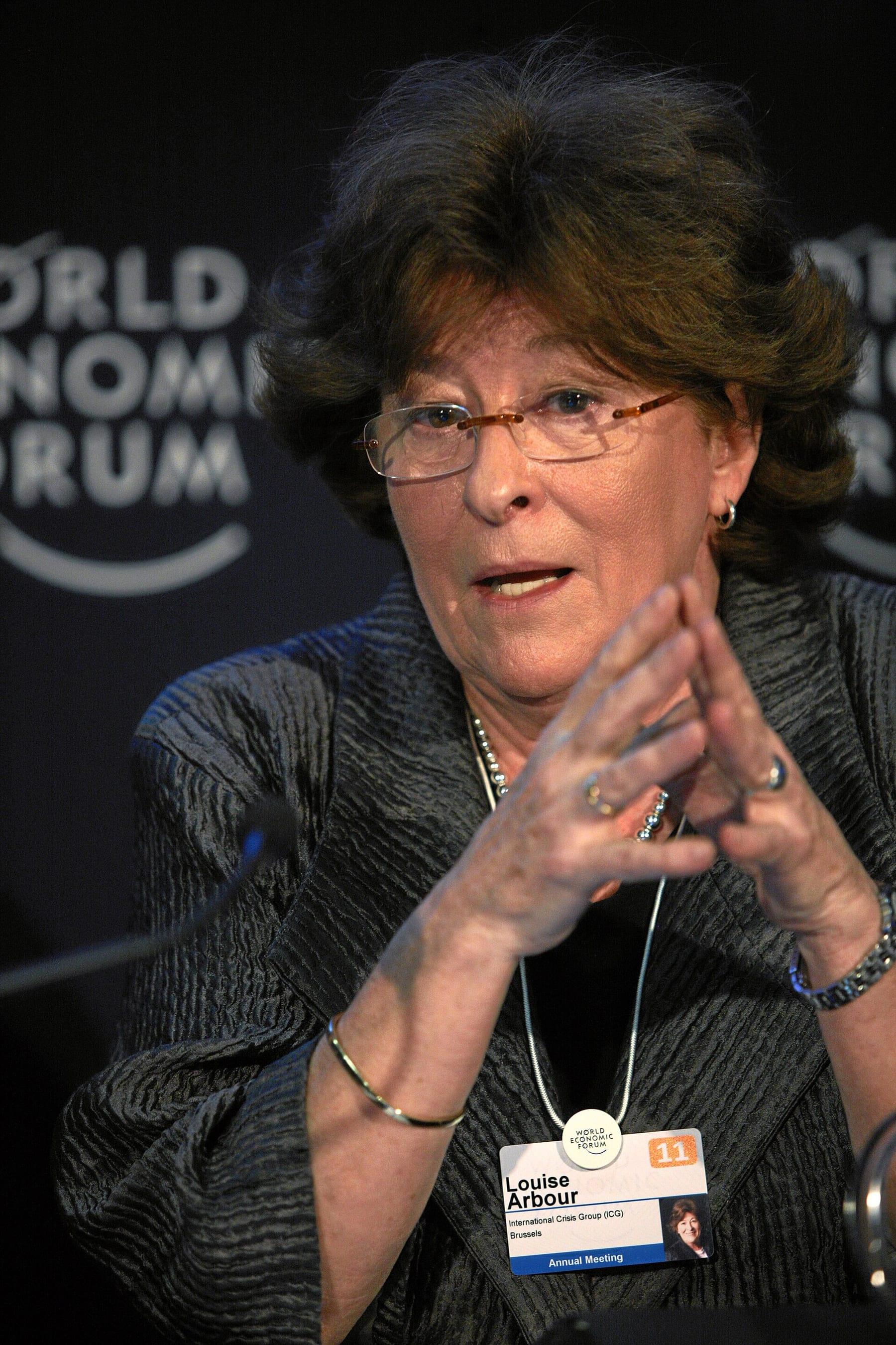 Woman with glasses and dark hair speaking and gesturing with her hands.
