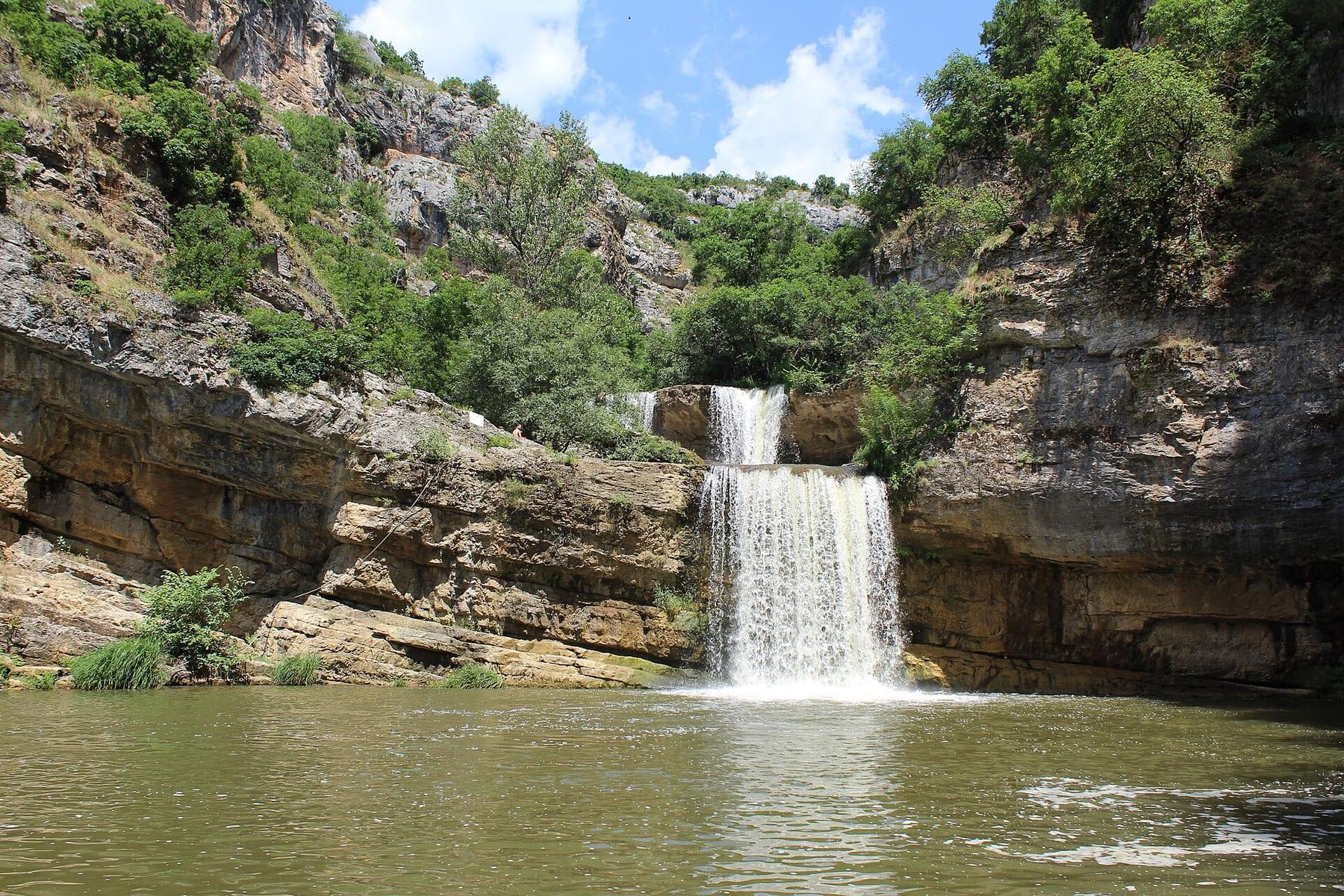 Waterfall dropping into a pool between rock walls.