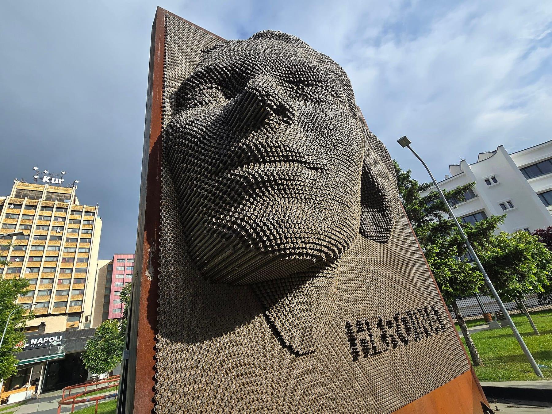 Large relief of a woman’s face made of thousands of metal medals, with the inscription “Heroinat”.