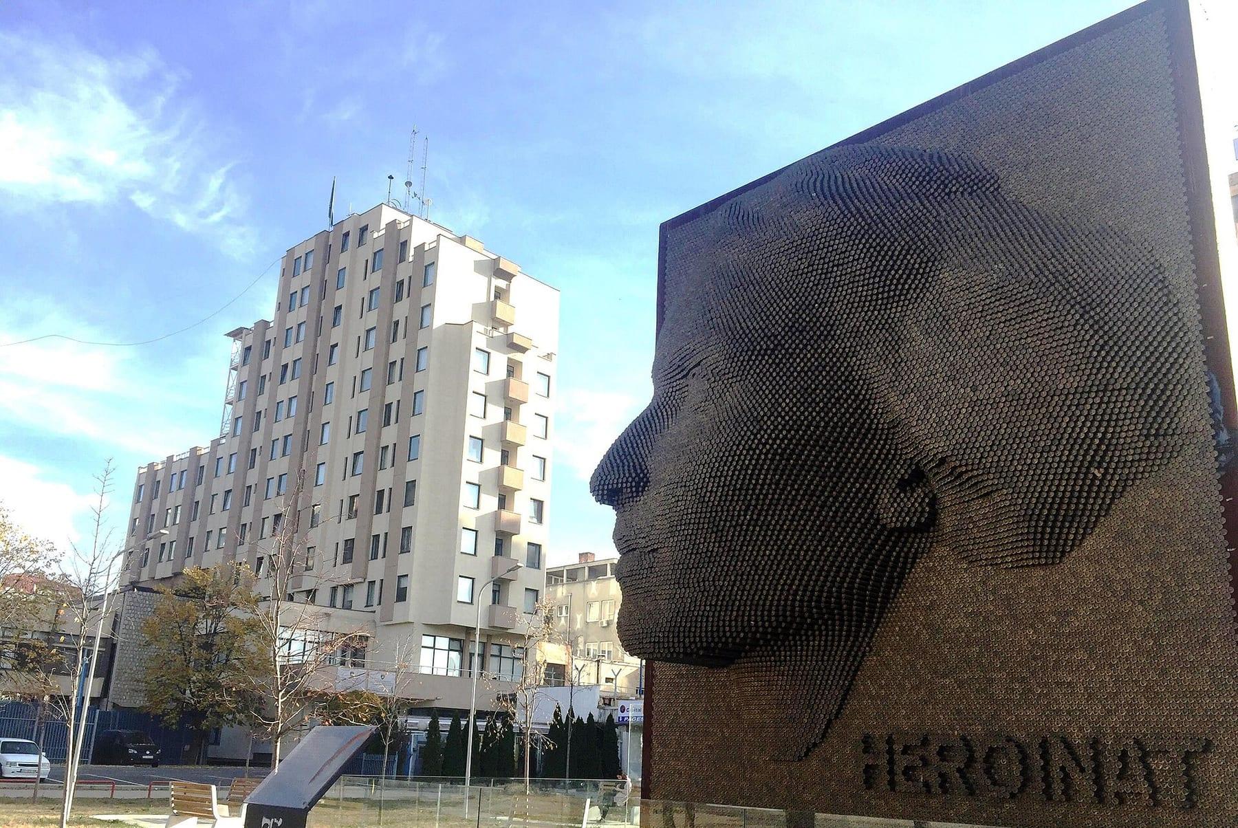 Side profile of the relief of the woman’s face, with apartment buildings behind.
