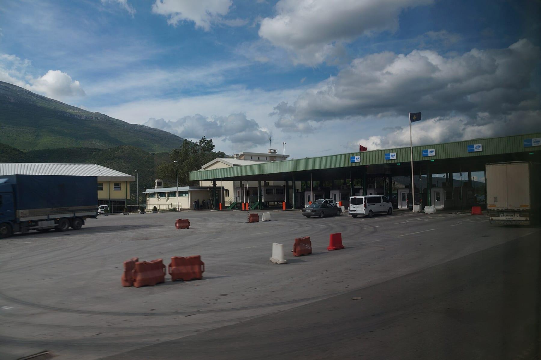 Forecourt and control booths of the border crossing with mountains behind.