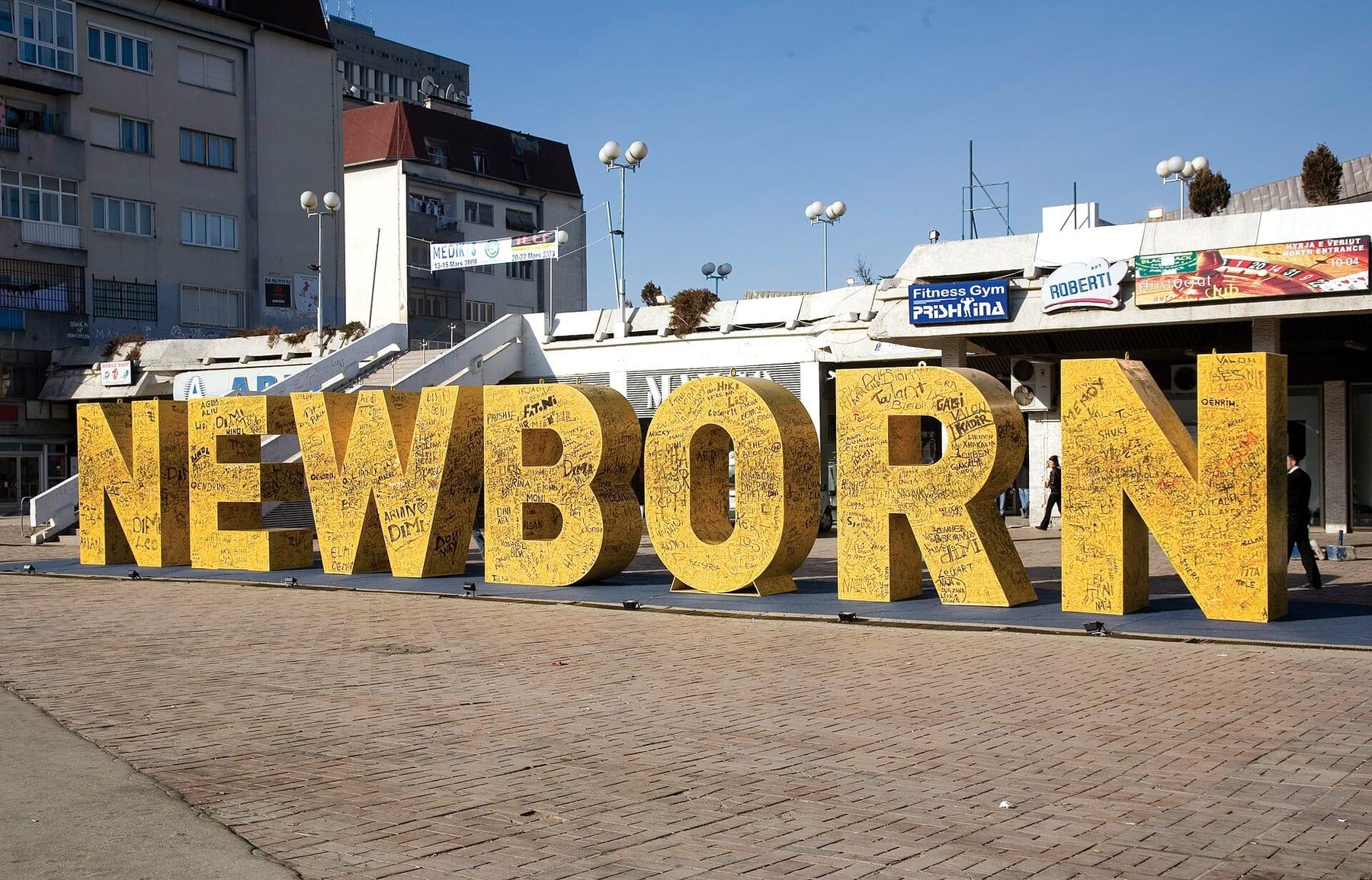 The large yellow NEWBORN letters covered in signatures on an empty square.