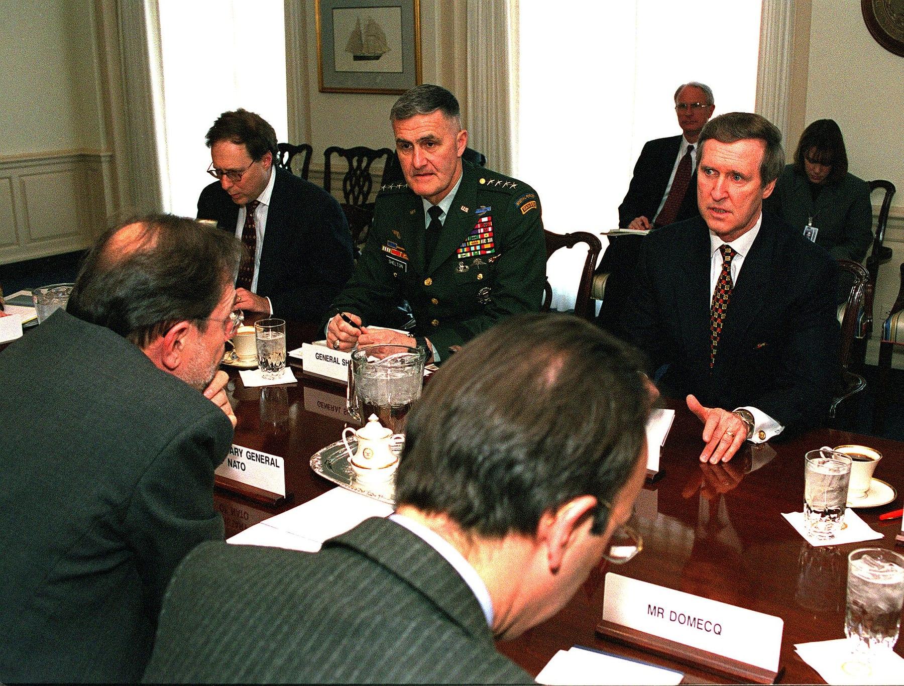 Civilian and military officials seated around a conference table.