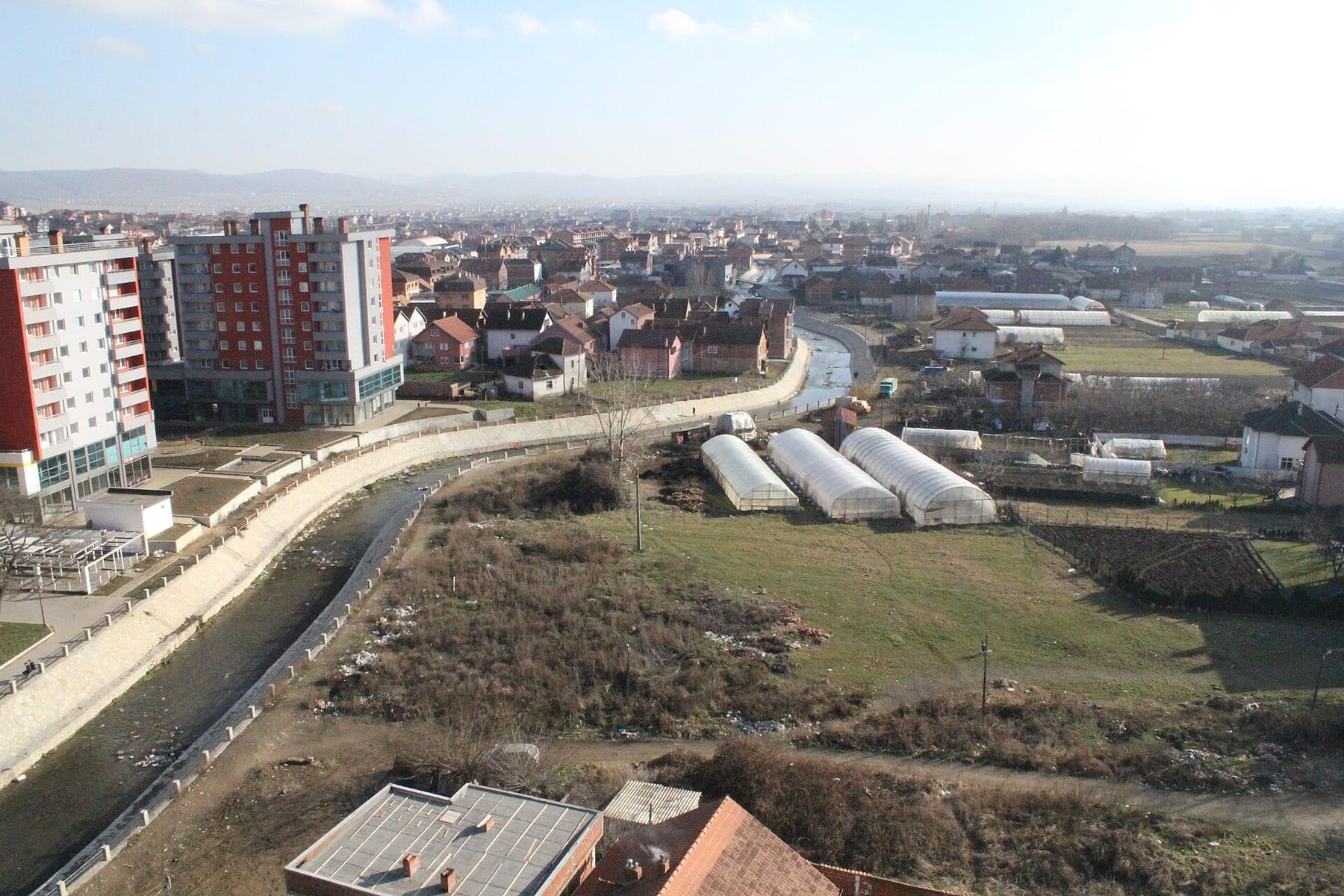 Town from above: channelled river, apartment blocks and red-roofed houses.