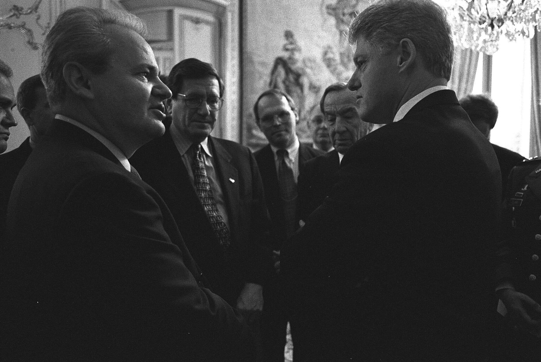 Black-and-white photo of two men talking face to face, with other officials in the background.