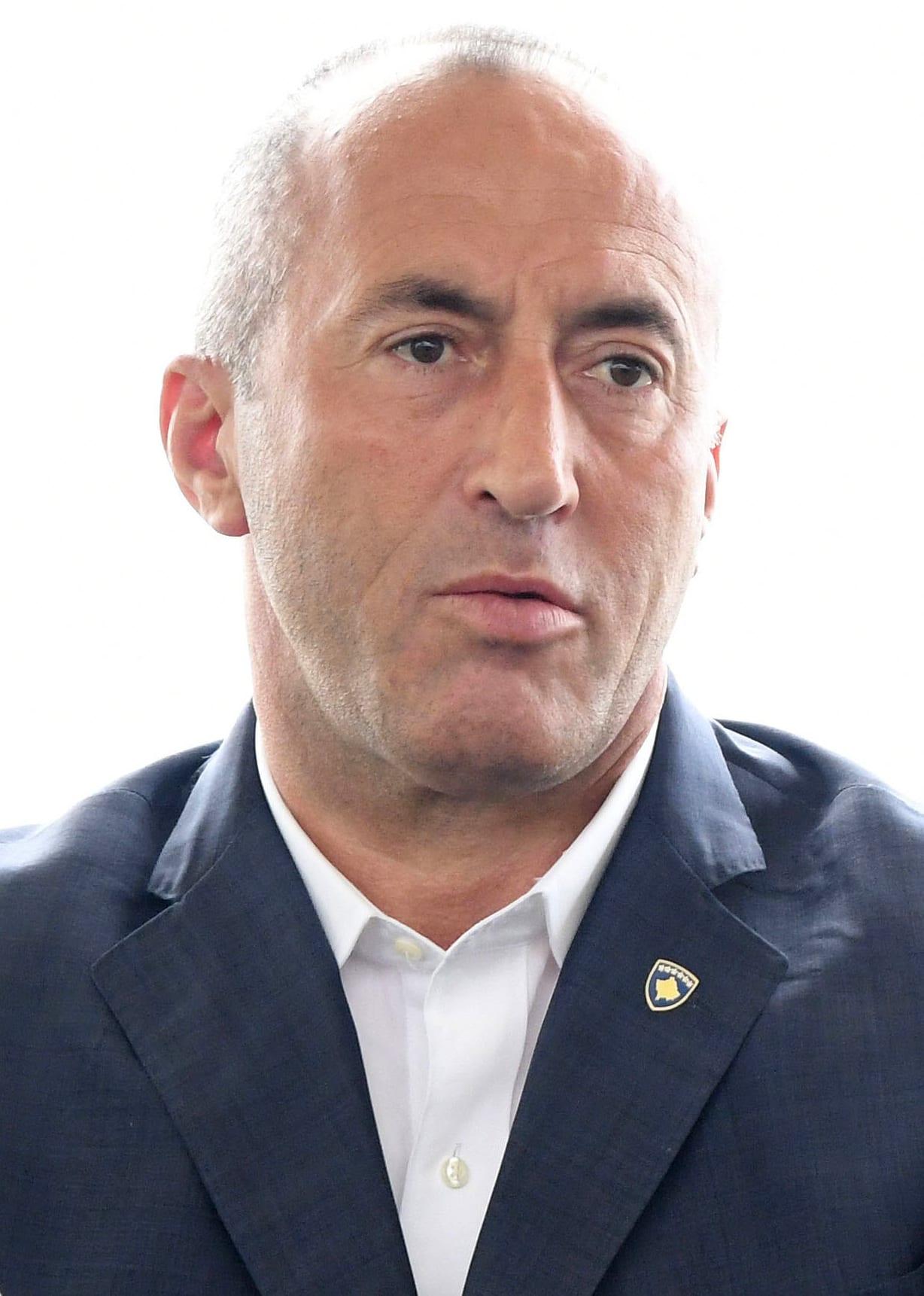 Portrait of a man in a dark jacket and white shirt against a white background.