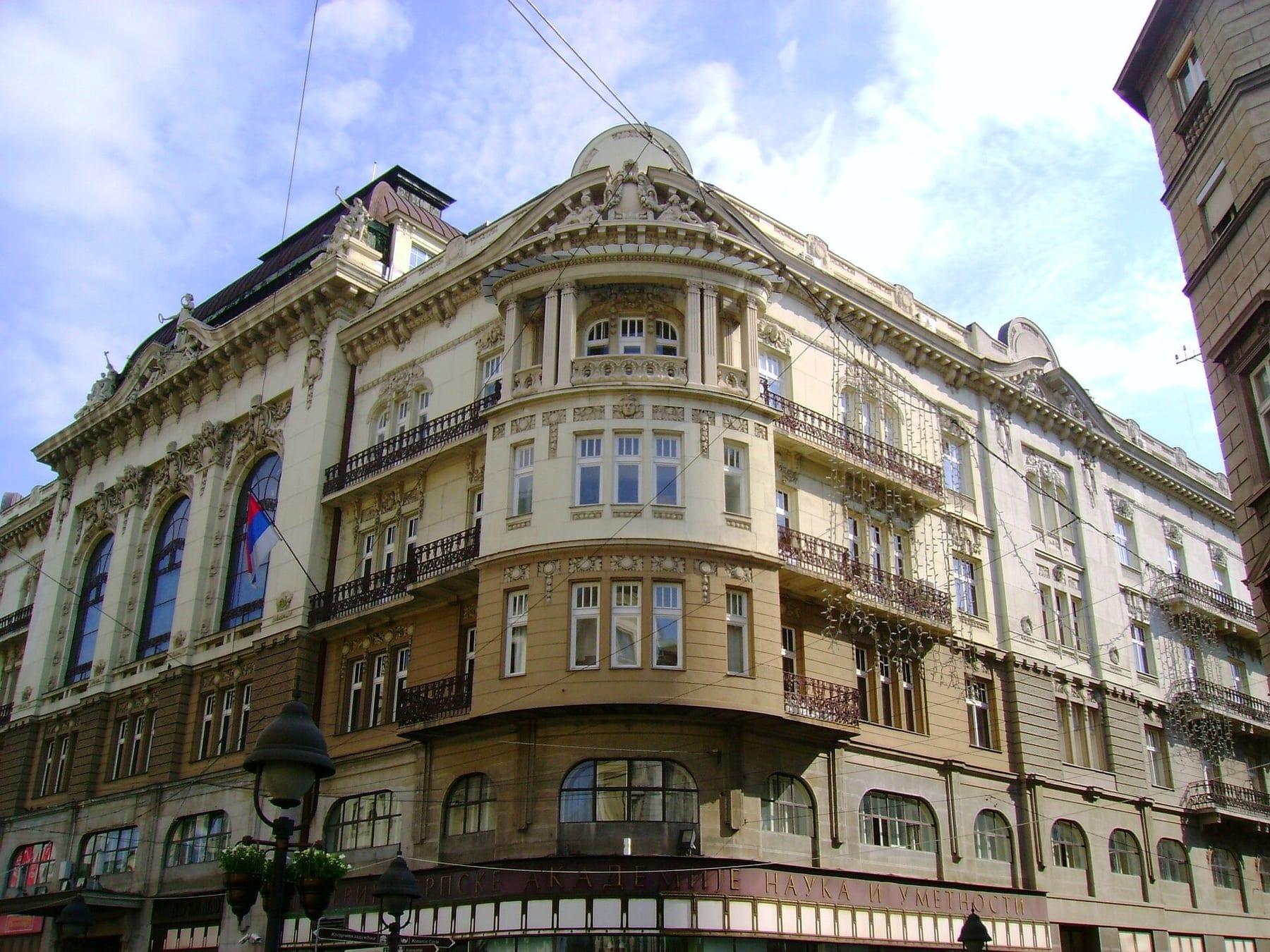 A monumental corner building with an ornate façade and dome, seen from the street.