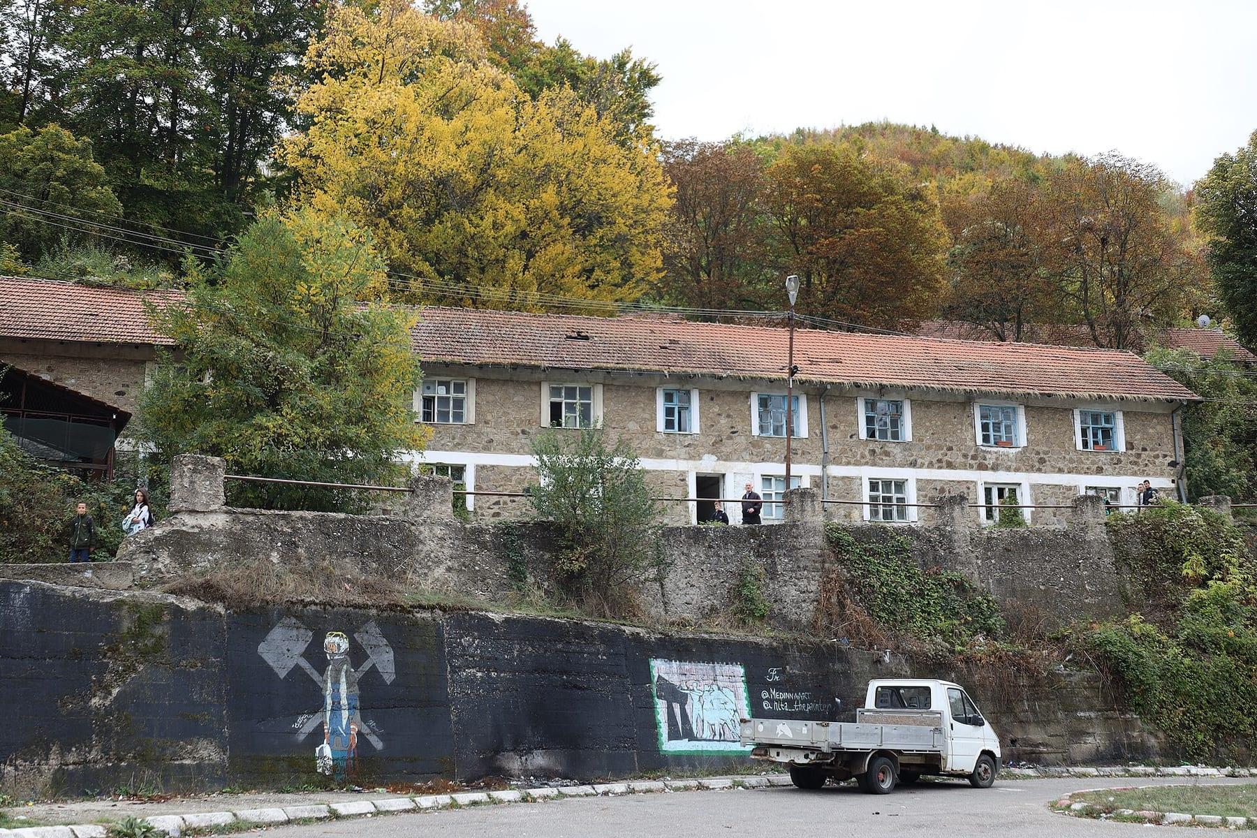Long two-storey housing block above a wall with a miners’ mural.