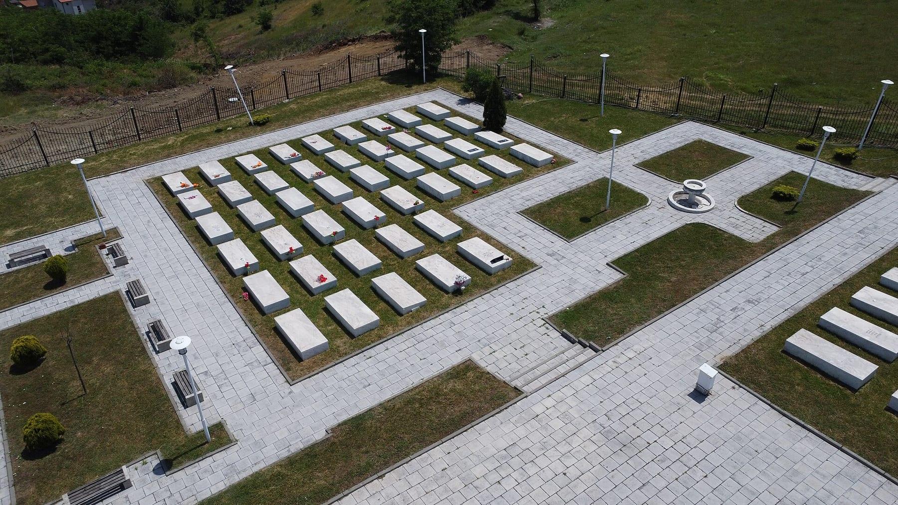 View from above of a cemetery complex with rows of white graves and paved paths.