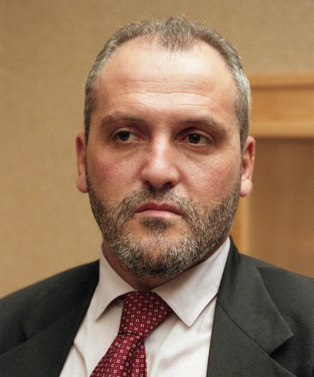 Portrait of a bearded man in a suit and red tie.