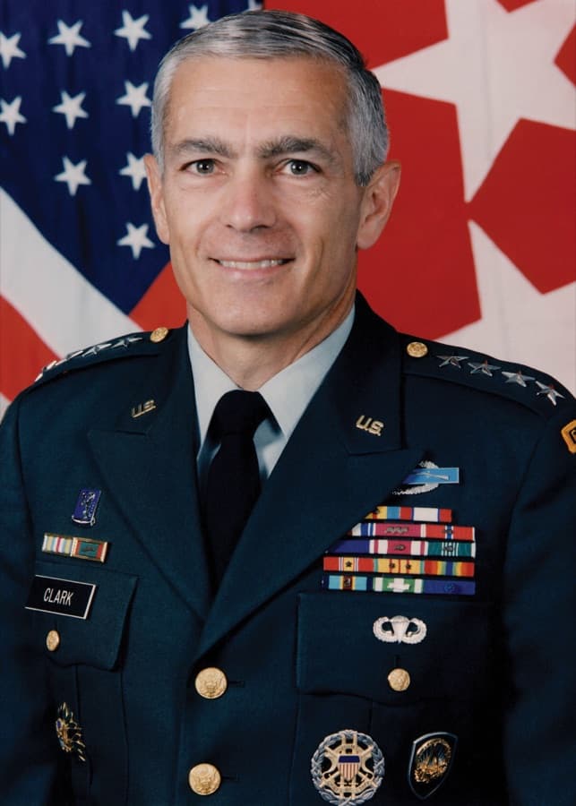 Official portrait of a US general in uniform with decorations, in front of flags